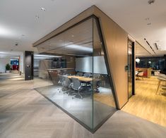 an office with glass walls and wooden flooring is seen in this image, there are desks on either side of the wall