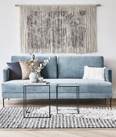 a living room with a blue couch and rugs on the wooden floor, two side tables