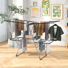 an ironing board with clothes hanging on it in a room next to a potted plant