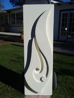 a white sculpture sitting on top of a lush green field in front of a house