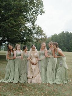 a group of women standing next to each other on top of a grass covered field