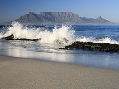 waves crashing on the beach with mountains in the background