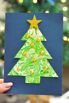 a hand holding up a card with a christmas tree made out of green and yellow paper