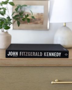 a book sitting on top of a dresser next to a lamp