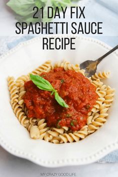 a white plate topped with pasta covered in sauce and garnished with basil leaves