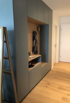 an empty room with a ladder in the middle and some cabinets on either side that are built into the wall