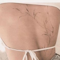 the back of a woman's body with flowers on it and white string tied around her waist