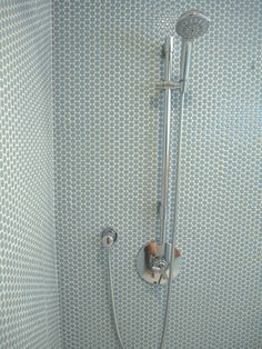 a shower head and hand held shower faucet in a bathroom with blue wallpaper