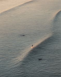 two surfers are riding the waves on their surfboards in the ocean at sunset