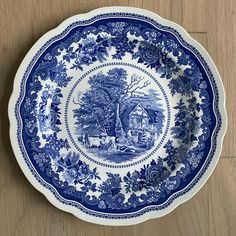 a blue and white plate sitting on top of a wooden table next to a wall