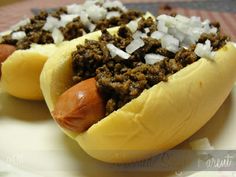 two hot dogs with chili and onions on a plate