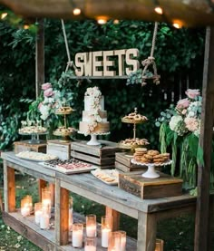 an outdoor dessert table with candles and cakes