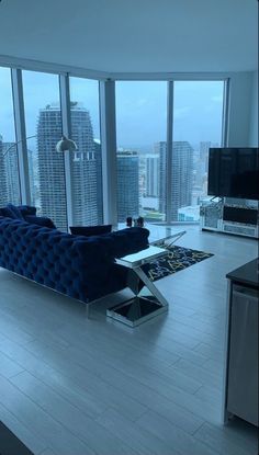 a living room filled with furniture next to tall windows and a flat screen tv on top of a hard wood floor