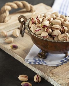 pistachios in a bowl on a wooden tray