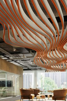 an office with orange and white lines hanging from the ceiling, chairs are in front of large windows