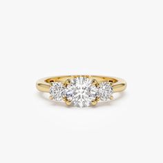 three stone engagement ring in yellow gold with diamonds on the sides and an oval diamond center