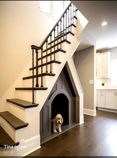 a dog is sitting in his house under the stairs