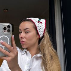 a woman taking a selfie in front of a mirror with her cell phone and headband