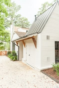 an instagram photo of a small white house with a metal roof and shingled windows