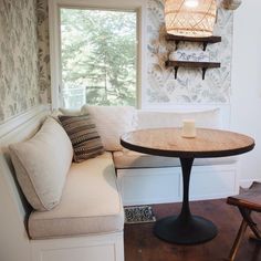 a table and bench in a room with wallpaper on the walls behind it, next to a window