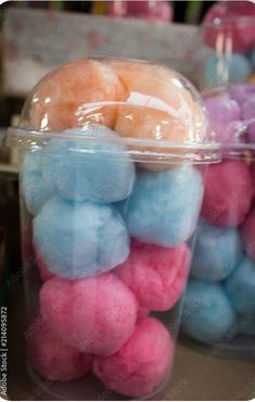 there are many different colored cotton balls in the plastic container on the table and one is pink, blue, and white