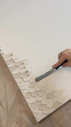 a person is using a knife to cut out circles on a sheet of white paper