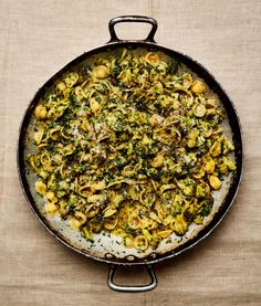 a skillet filled with pasta and broccoli on top of a brown table