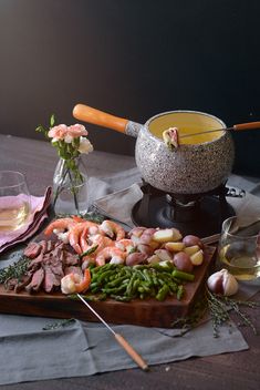 a table topped with food and wine next to a vase filled with flowers on top of a table