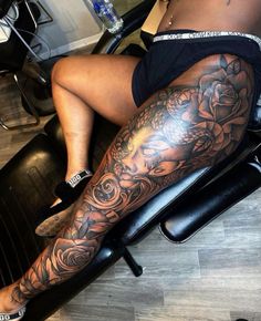 a woman sitting in a chair with tattoos on her legs