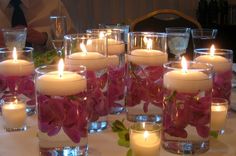 many candles are lit on a table with flowers