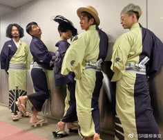 several people in kimonos are lined up against a wall