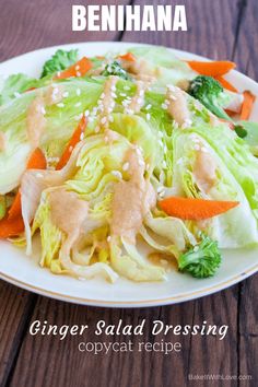 a white plate topped with lettuce and carrots covered in dressing next to broccoli