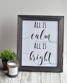 a framed sign that says all is calm, all is bright next to a potted plant