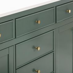 a green dresser with brass handles and knobs