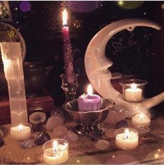 candles are lit in front of a crescent shaped candle holder on a table with other items