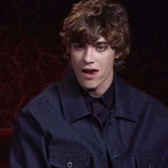 a young man with curly hair wearing a black shirt