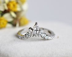 a diamond ring sitting on top of a white surface next to flowers and a vase