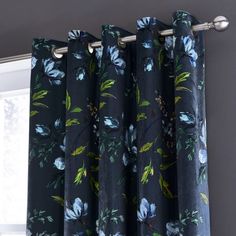 the curtains are hanging in front of the window with blue flowers on them and green leaves