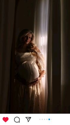 a pregnant woman standing in front of a window