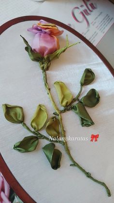 there is a rose that has been placed on the table top with leaves and flowers