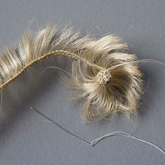 a pair of scissors and a piece of hair on a gray surface with white thread