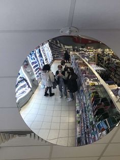 people are standing in a store looking at their cell phones and taking pictures through the mirror