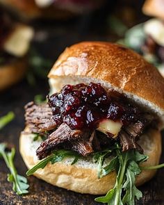 a sandwich with meat and cranberry sauce on it sitting on a wooden table