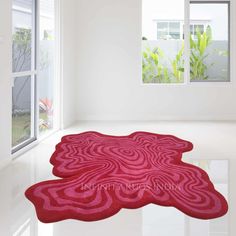 a red rug is in the middle of a white room with large windows and plants