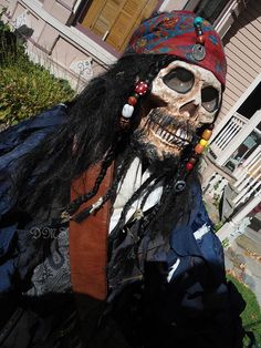 a skeleton wearing a pirate costume in front of a house