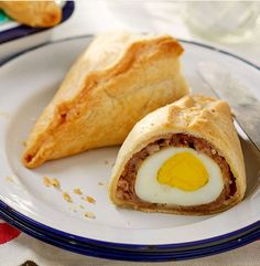 an egg roll is on a plate with a knife and fork next to the pastry