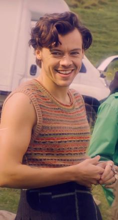 a young man smiles as he stands in front of other people and holds his hands together