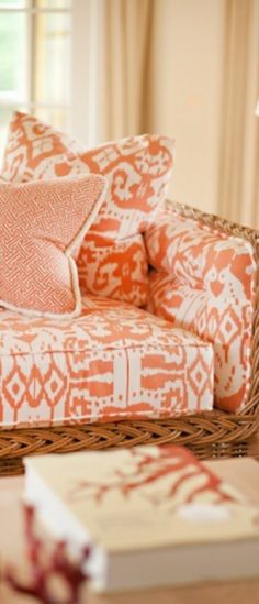 an orange and white couch sitting in a living room next to a table with books on it