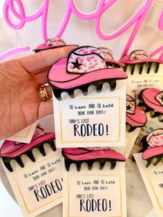 a person holding up some pink and black cupcakes with name tags on them