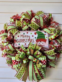 a christmas wreath with green and red bows on the front, merry christmas sign in the center